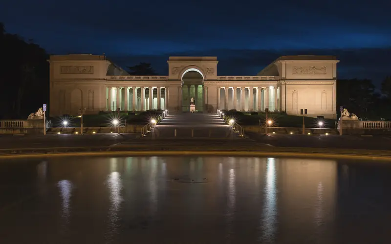 Photo of the Legion of Honor lit up at night above its reflecting pool